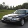 A luxury sedan parked next to an immaculate lawn with palm trees